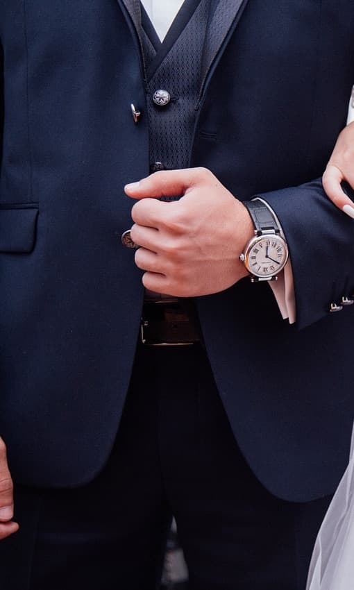 A groom in a navy suit fastening his cuff